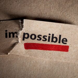 Piece of paper with the word 'Impossible' torn after the 'Im' to read 'possible' underlined in red.